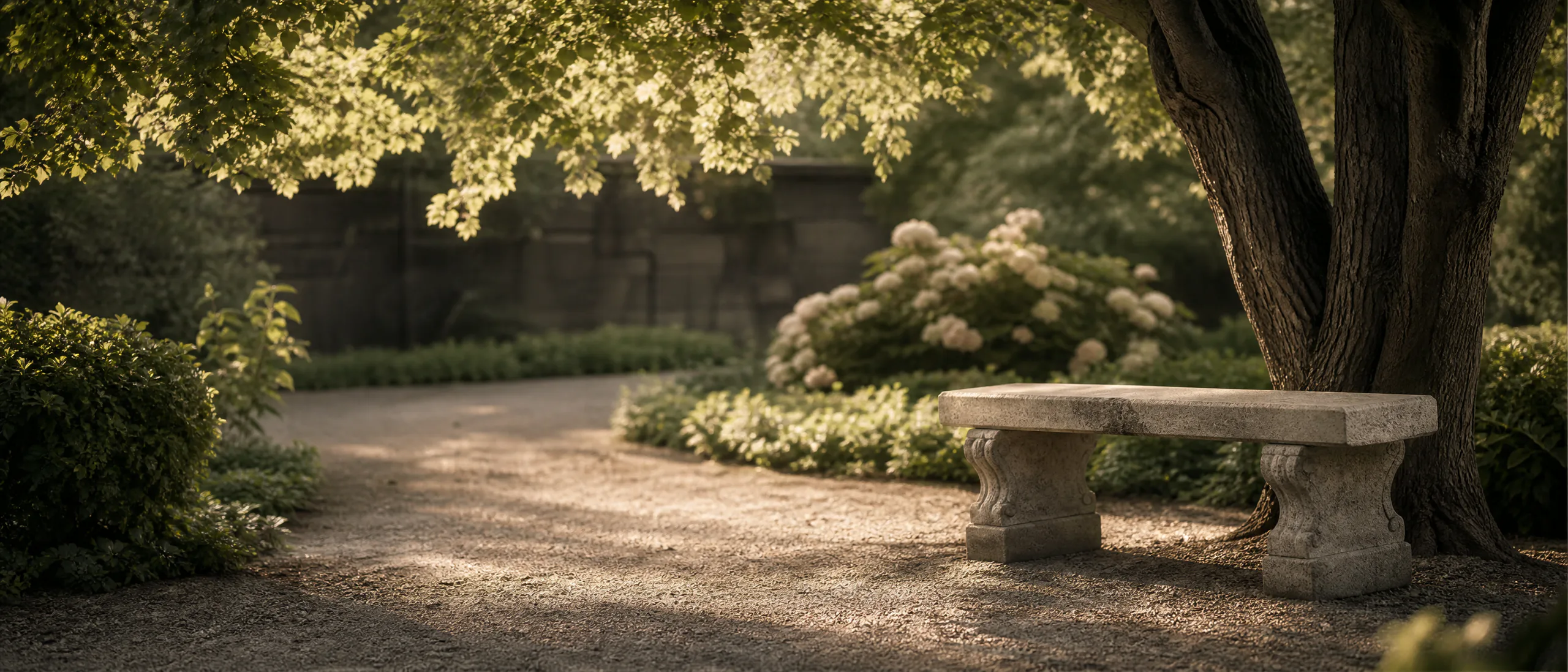 A quiet memorial garden with a stone bench under mature trees